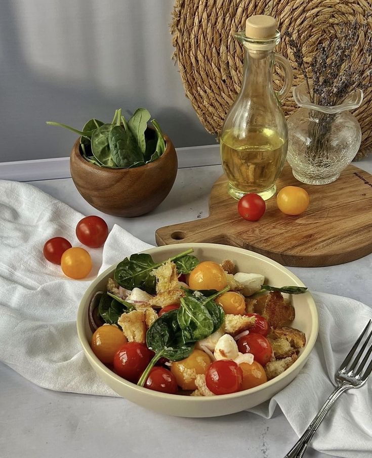 Fresh tomato and spinach salad with mozzarella, olive oil, and croutons, served on a white cloth background.