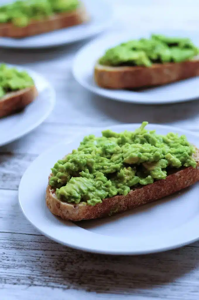 Avocado toast on a white plate with rustic crust, perfect for a healthy breakfast or brunch.