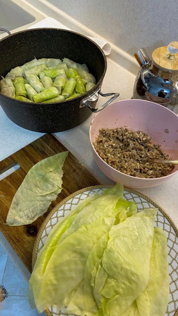 Preparing cabbage rolls with stuffing in a kitchen, in a pot and on a table, for a homemade meal.
