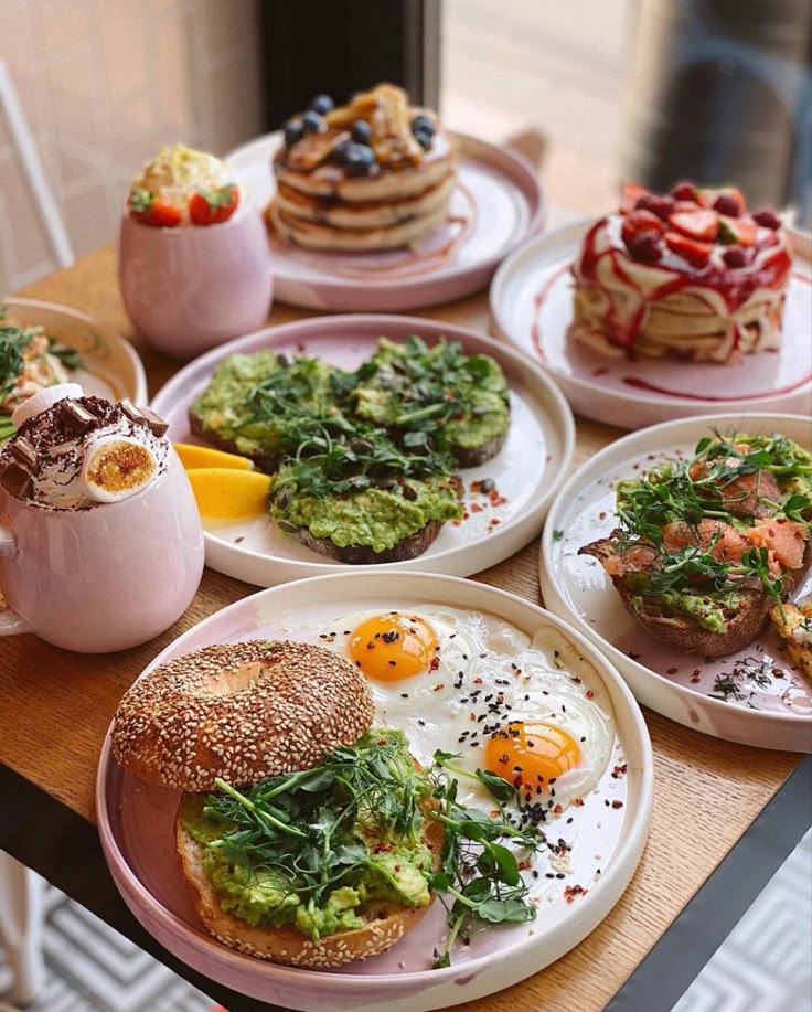 Assorted brunch dishes with pancakes, avocado toast, eggs, and fruit; perfect for a cozy cafe experience.