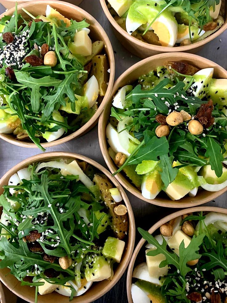 Fresh salad bowls with boiled eggs, arugula, nuts, and seeds in eco-friendly containers. Perfect for a healthy meal.