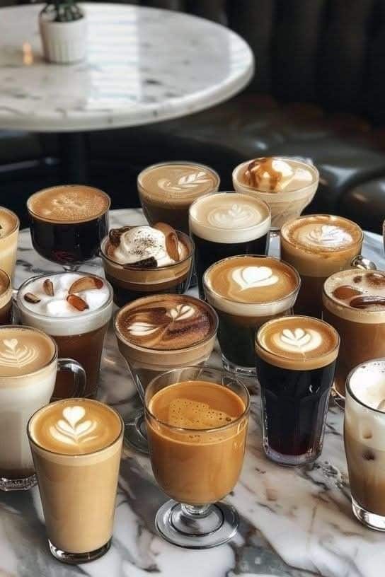 Assorted coffee drinks with latte art on a marble table, creating a cozy café atmosphere.
