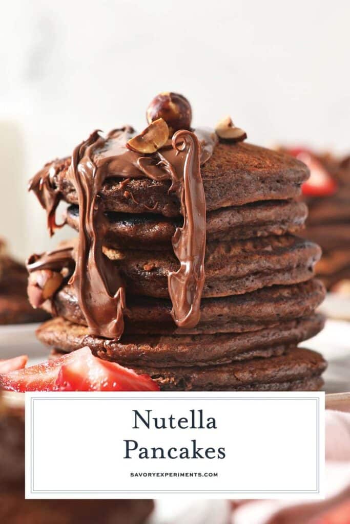 Stack of chocolate pancakes topped with Nutella and hazelnuts, garnished with fresh strawberries.
