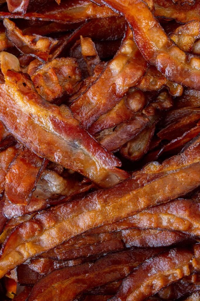 Crispy cooked bacon strips piled up, showcasing golden-brown texture and savory appeal. Perfect for breakfast lovers.
