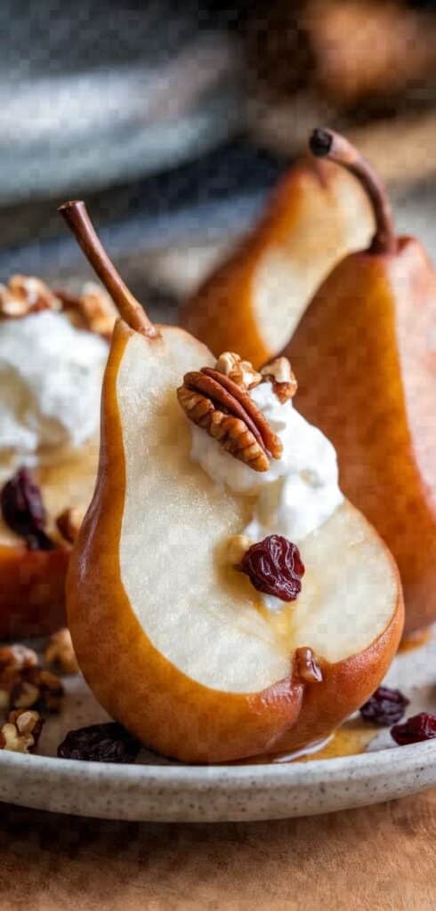 Halved pear with cream cheese, pecan, and cranberries on a plate, creating a delicious dessert presentation.
