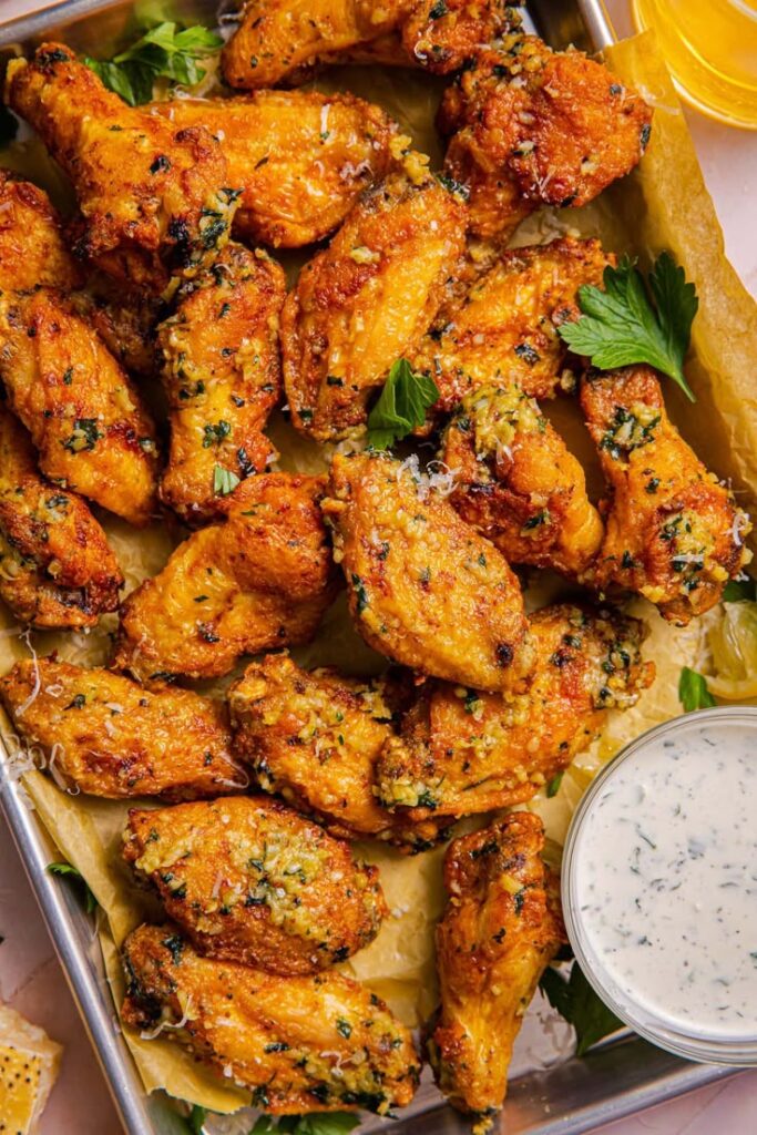 Crispy Garlic Parmesan Wings Air Fryer - 10 Crowd-Pleasing Appetizers That Will Wow Your Party | Crispy garlic parmesan chicken wings on a tray with fresh herbs and dipping sauce. Perfect for parties or game day snacks.