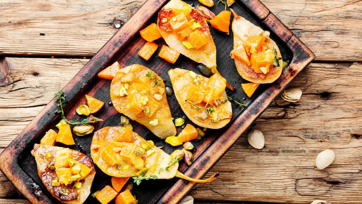 Depositphotos_309145526_XL - Baked Pear Dessert Ideas for Easy and Delicious Treats | Roasted pear slices with chopped nuts and diced pumpkins on a rustic wooden platter. Delicious autumn dessert.