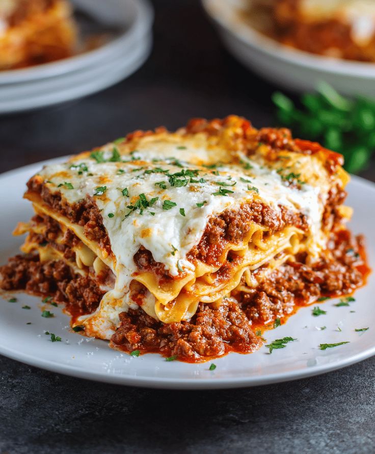 Delicious homemade lasagna with rich meat sauce and melted cheese, garnished with fresh parsley on a white plate.