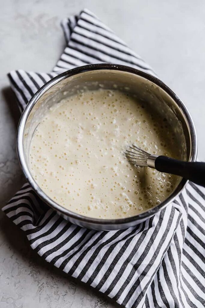 Bowl of batter on a striped cloth with a whisk, perfect for baking and cooking preparations.