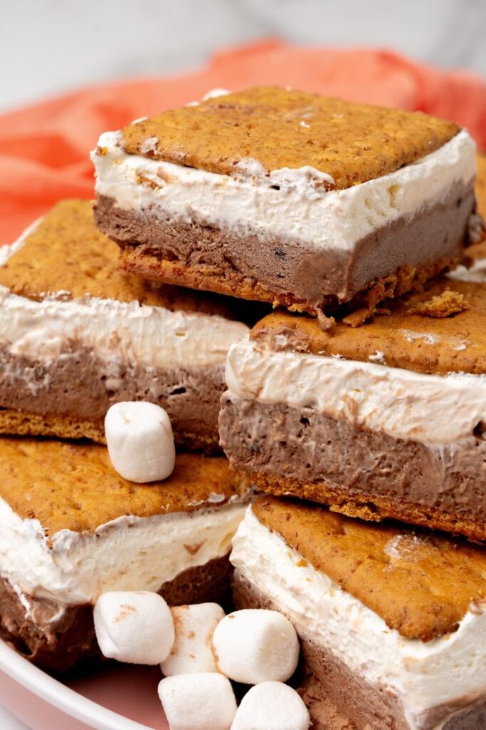Delicious ice cream s'mores bars with chocolate, marshmallow, and graham crackers on a plate.