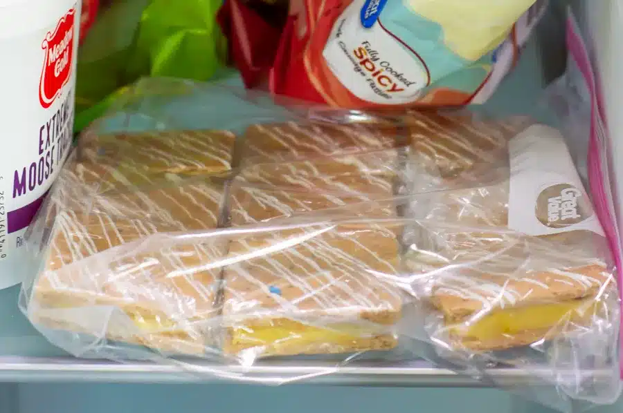 Frozen pop-tarts in a bag beside ice cream and snacks in a freezer drawer.
