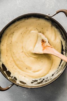 Creamy mashed potatoes being stirred in a pot with a wooden spoon, perfect side dish.