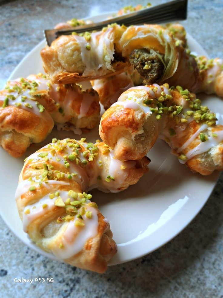 Plate of pistachio-filled pastries with glaze, displayed on a table. Perfect for dessert or a sweet snack.