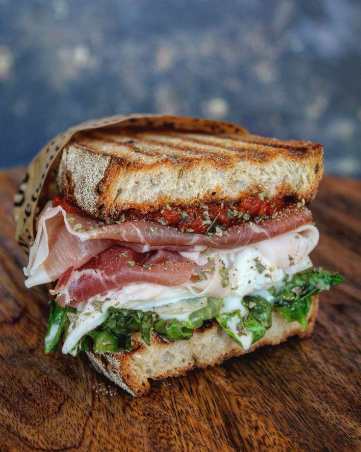 Delicious gourmet sandwich with prosciutto, fresh greens, and cheese on grilled artisan bread.