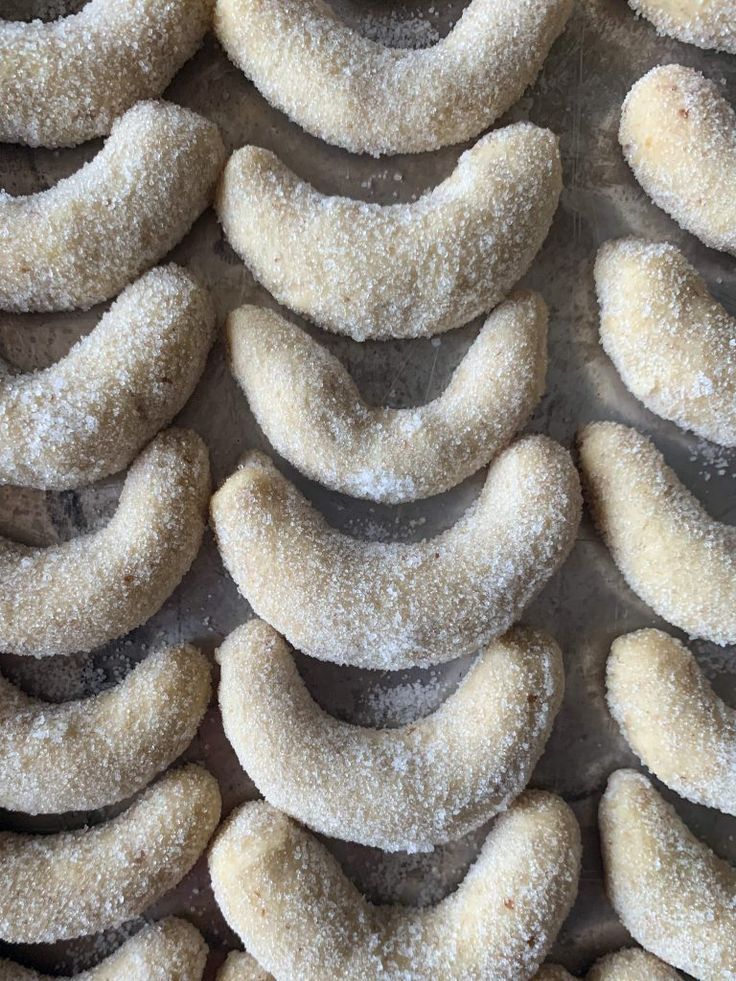 Sugar-coated crescent cookies lined up on a baking tray, perfect for festive treats and holiday baking.