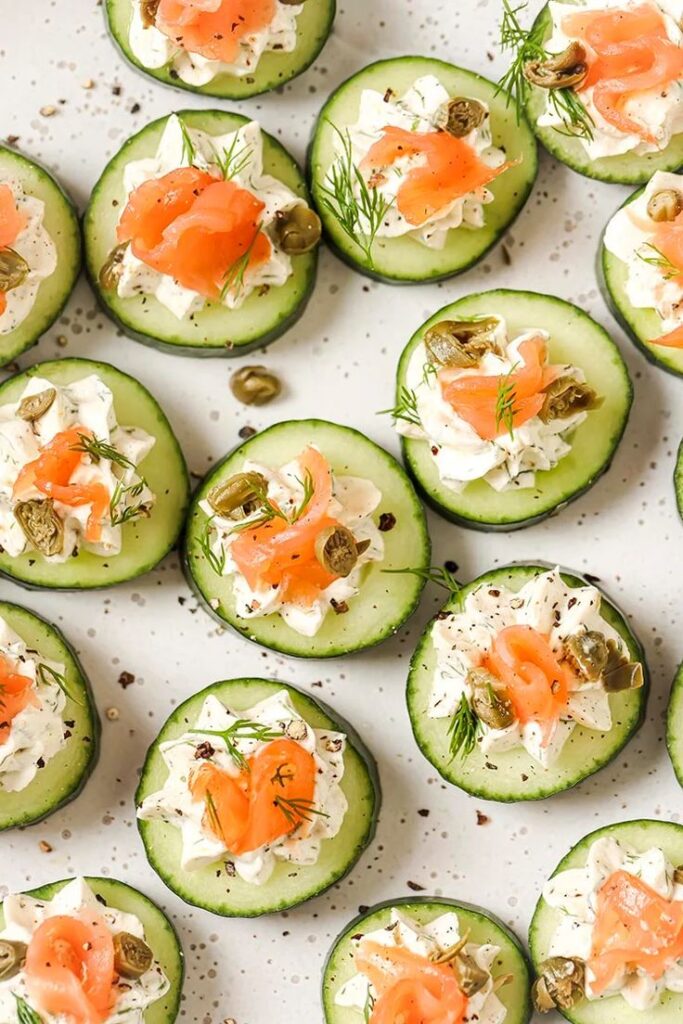 When Life Gives You Cucumbers Make This Smoked - 10 Crowd-Pleasing Appetizers That Will Wow Your Party | Cucumber slices topped with cream cheese, smoked salmon, capers, and dill on a white plate for a tasty appetizer.
