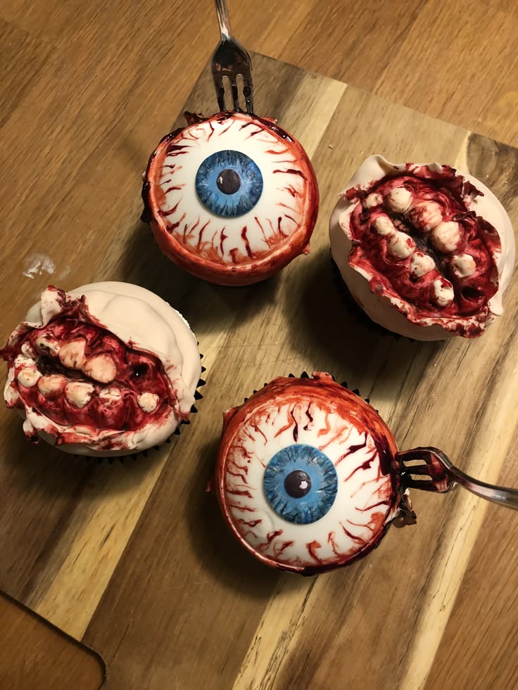 Halloween cupcakes with realistic eyeball and teeth designs on a wooden board.