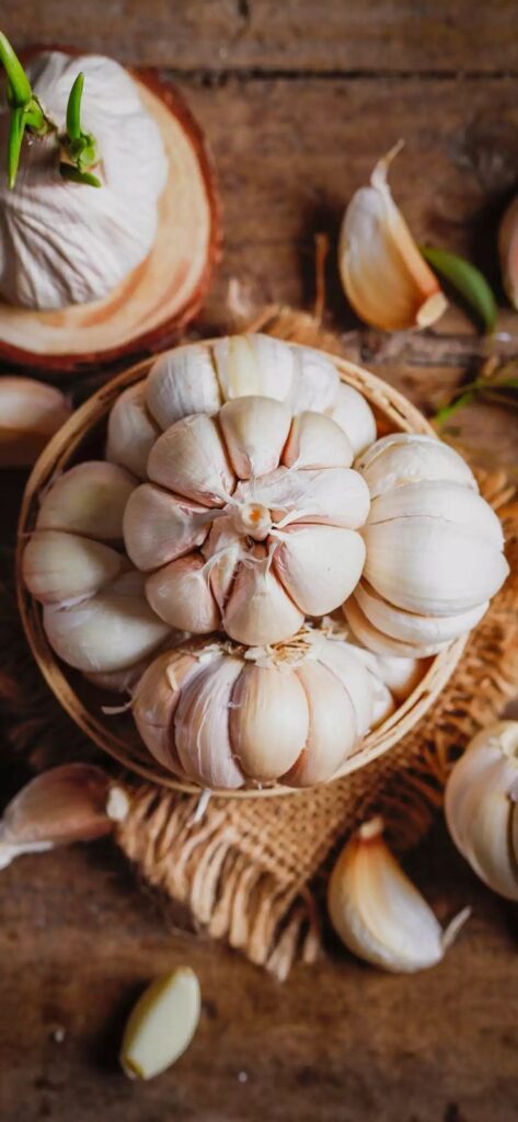 Fresh garlic bulbs in a rustic basket on a wooden table, perfect for cooking and seasoning.