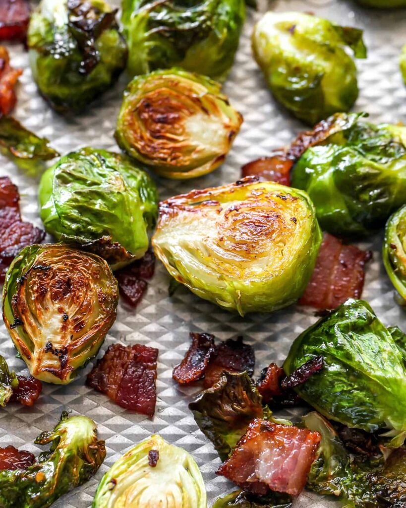 Roasted Brussels sprouts with crispy bacon on a baking sheet, showcasing a deliciously caramelized texture.