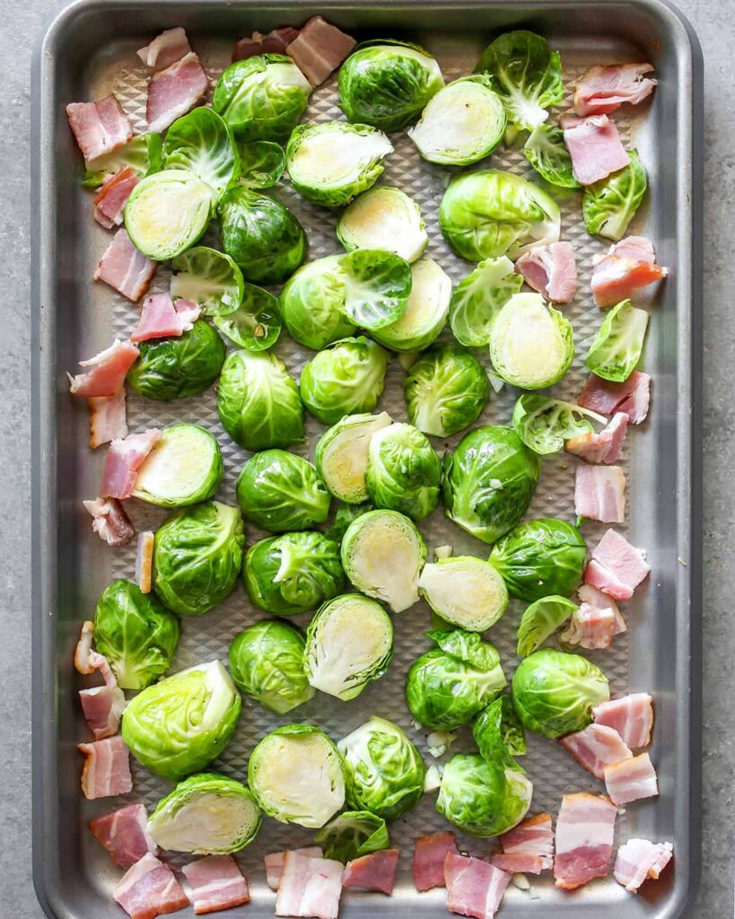 Brussels sprouts and bacon on a baking tray ready for roasting, a perfect combination for a flavorful side dish.