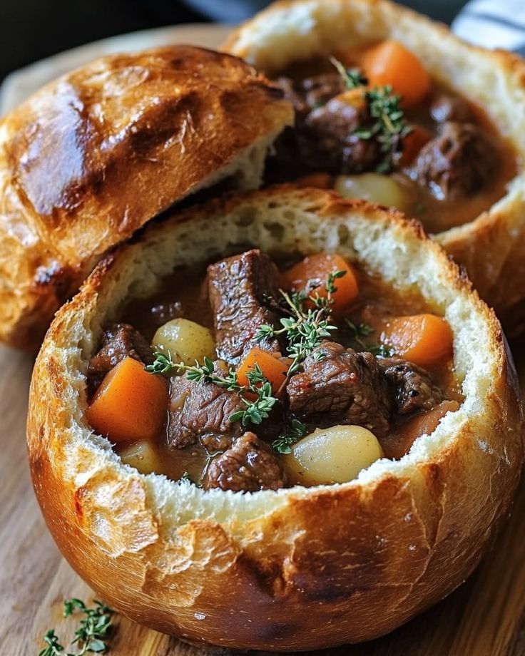 Hearty beef stew served in a bread bowl, garnished with fresh thyme, showcasing comforting homemade cuisine.