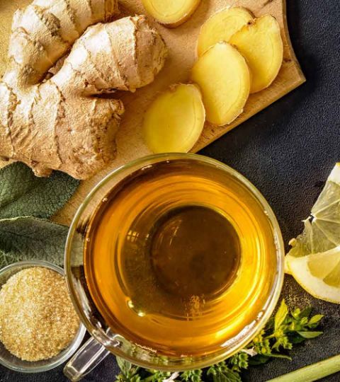 Organic Pure Ginger Tea Bags - 200 Tea Bags - Soothing Ginger Honey Tea: Your Cozy Comfort Brew - Chief Stories Cup of ginger tea with fresh ginger slices, lemon, sugar, and herbs on a wooden board. Perfect for a refreshing drink.