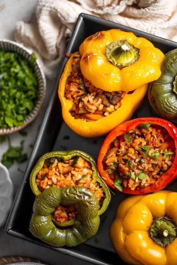 Vegan Stuffed Peppers - Classic Stuffed Peppers Recipe Colorful stuffed bell peppers filled with rice and herbs, served in a black tray for a delicious meal.
