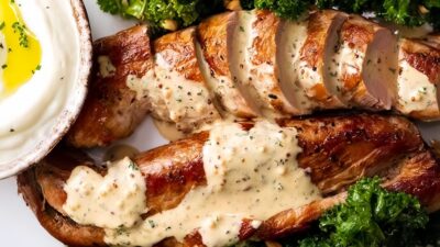 Sliced pork tenderloin with creamy mustard sauce, served with kale and yogurt dip. Perfect for a gourmet meal.