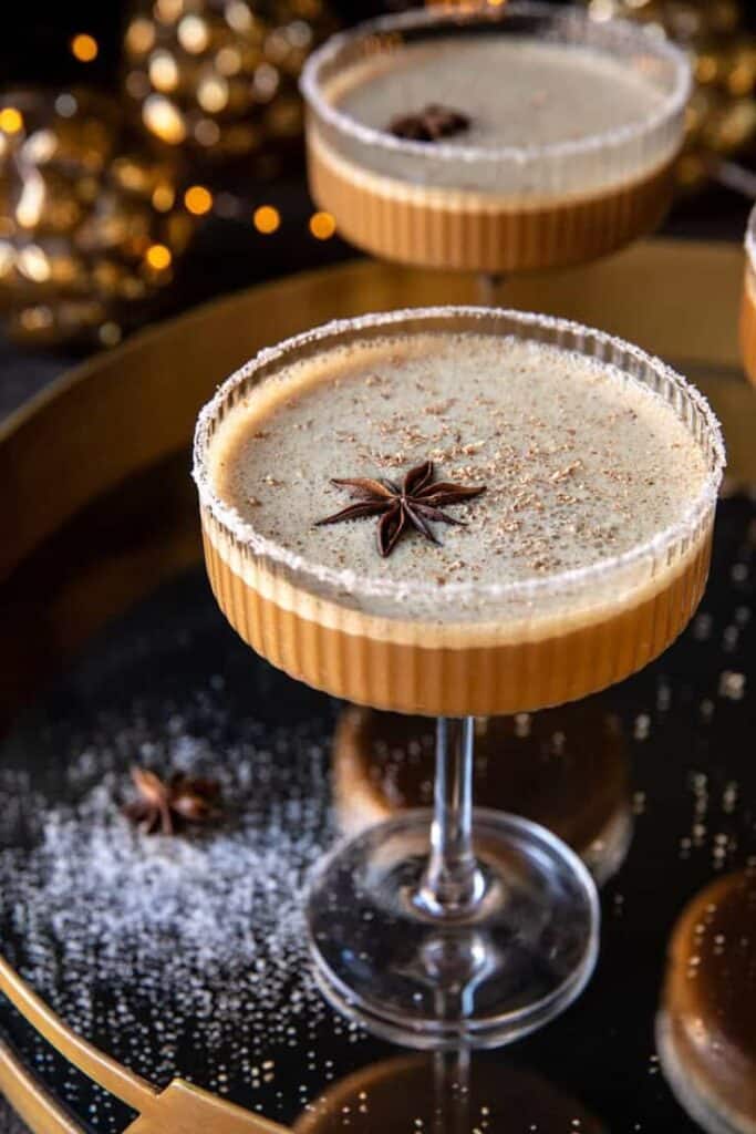 Creamy holiday cocktail with star anise garnish in a glass on a festive tray.