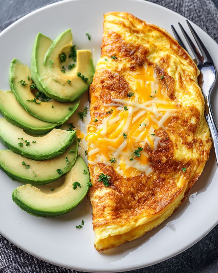 Cheese omelette with sliced avocado on a plate, garnished with parsley, next to a fork. Healthy breakfast option.