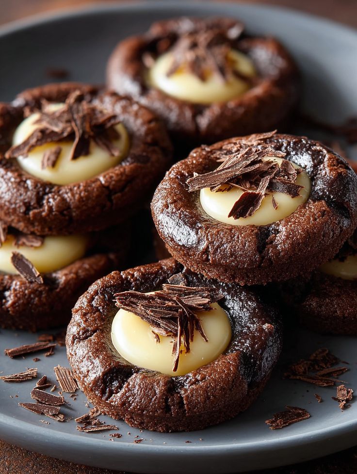 Rich chocolate cookies with creamy centers and chocolate shavings on top, served on a gray plate. Perfect dessert treat!