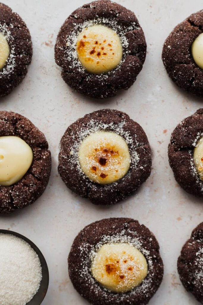 Chocolate cookies with creamy centers, dusted with sugar, arranged on a light surface.