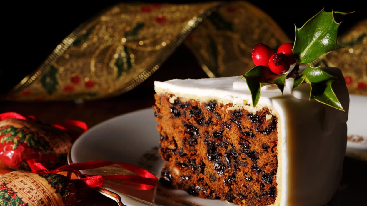 Depositphotos_11458631_XL - Festive Christmas Cake Decor Ideas Slice of festive fruitcake with icing and holly on a plate, rich Christmas dessert.
