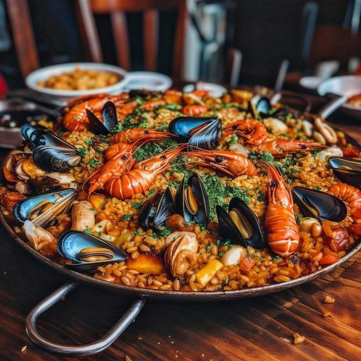 Delicious seafood paella with shrimp, mussels, and rice served in a large pan on a wooden table.