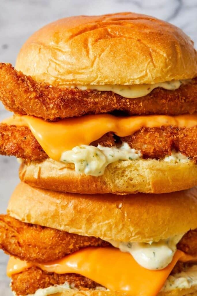 Close-up of a double crispy chicken sandwich with melty cheese and creamy sauce on a soft bun.