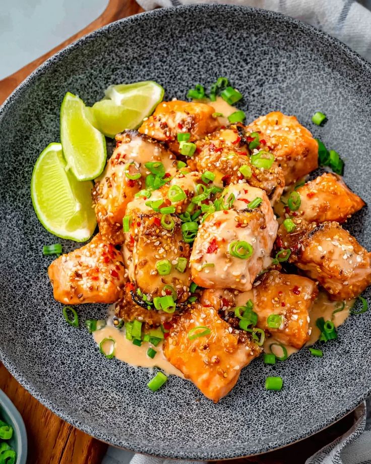 Bang Bang Salmon 1 - Bang Bang Salmon Recipe - Easy & Flavorful Fish Spicy glazed salmon bites garnished with green onions and lime slices on a stylish gray plate.