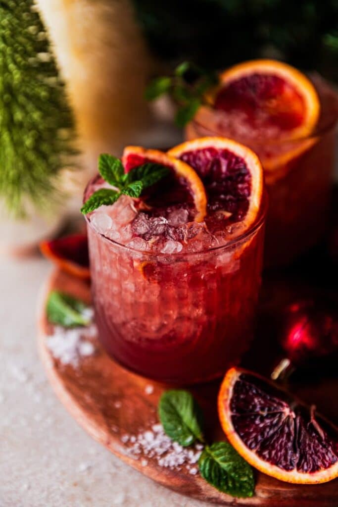 Blood Orange Palomas cocktail mocktail - Festive & Easy: Master the Perfect Pomegranate Paloma Refreshing blood orange cocktail with mint garnish on a wooden tray, perfect for a festive holiday drink.