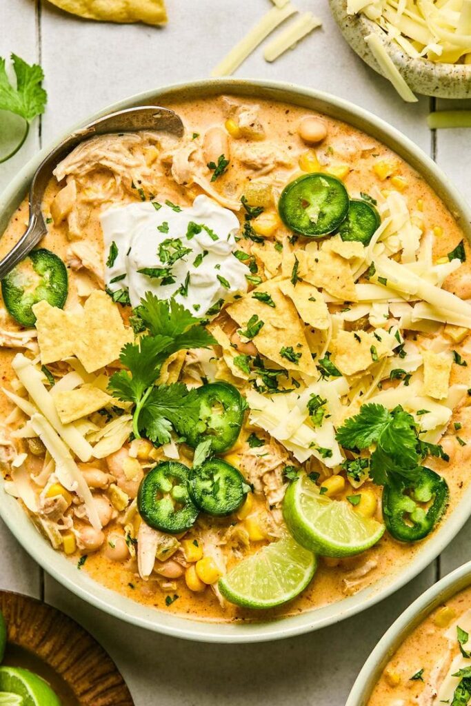 Creamy Dairy-Free White Chicken Chili - Your Guide to Delicious White Chicken Chili with Easy Tips Creamy chicken chili with beans, topped with cheese, jalapeños, sour cream, and fresh cilantro in a bowl.
