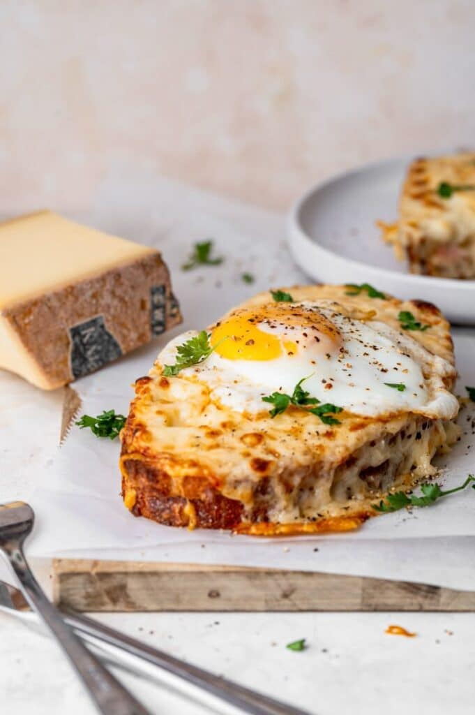 Croque Madame - Food From ClaudNine - Insider Tips for a Delicious, Gourmet Croque Madame Cheesy croque madame with a sunny-side-up egg and parsley served on rustic bread, perfect for brunch enthusiasts.