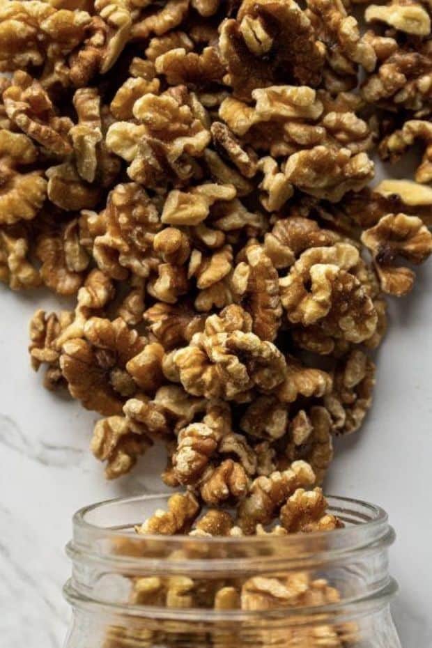 English Walnuts Fresh Heart-Healthy by Mountain Man Nut Fruit Co_ - Make Delicious Chicken Salad with Walnuts & Cheese in Minutes Walnuts spilling from a glass jar onto a white surface, showcasing healthy, raw nuts for a nutritious snack.