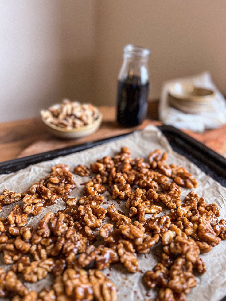 Honey Roasted Walnuts - Make Delicious Chicken Salad with Walnuts & Cheese in Minutes Candied walnuts cooling on parchment paper, jar of syrup and bowl of nuts in the background. Perfect for snacks or toppings.