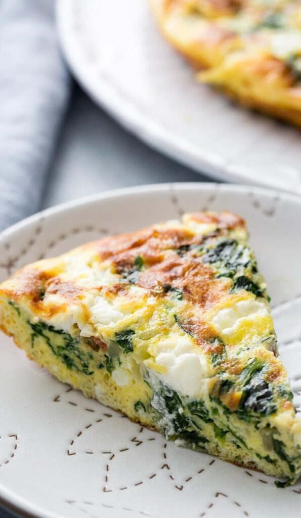 Make a Spinach Frittata for an All-in-One Meal - Easy Christmas Breakfast Recipes for Joyful Mornings Slice of spinach and cheese frittata on a plate, perfect for a healthy breakfast or brunch option.