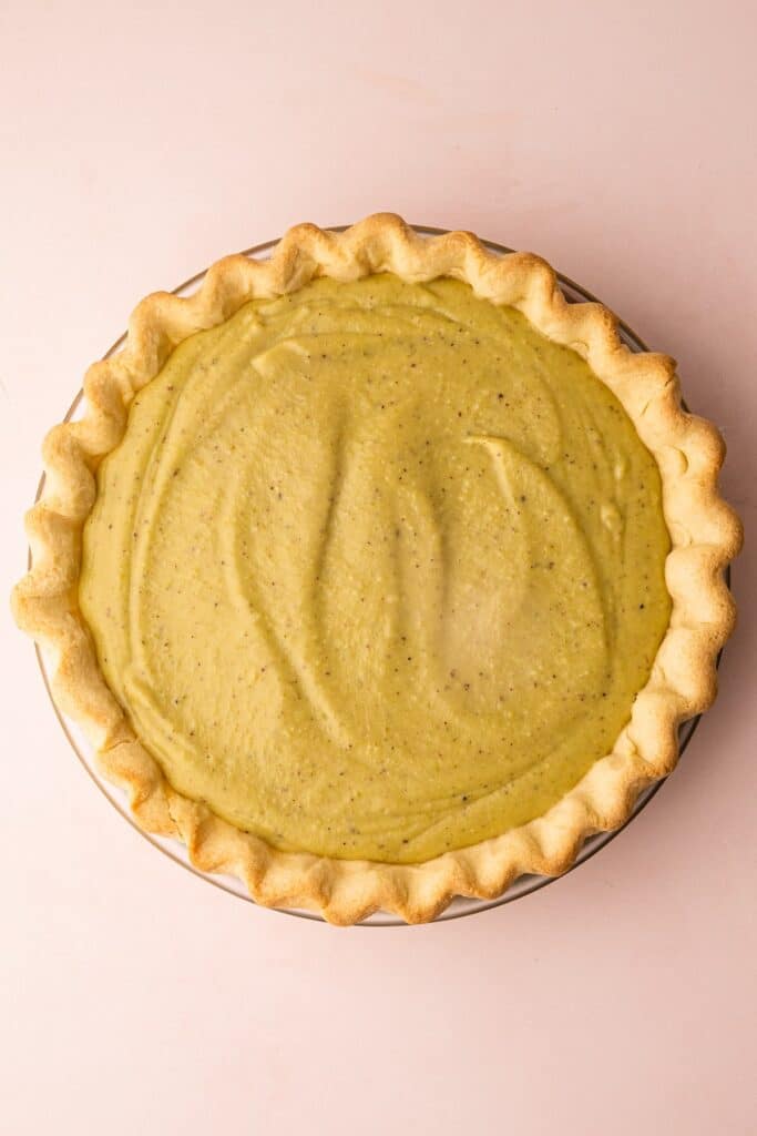 Pistachio-cream-pie-40 - Delicious Pistachio Pie Ideas for Parties and Holidays Creamy pistachio pie with a golden crust on a soft pink background, perfect dessert for spring gatherings.