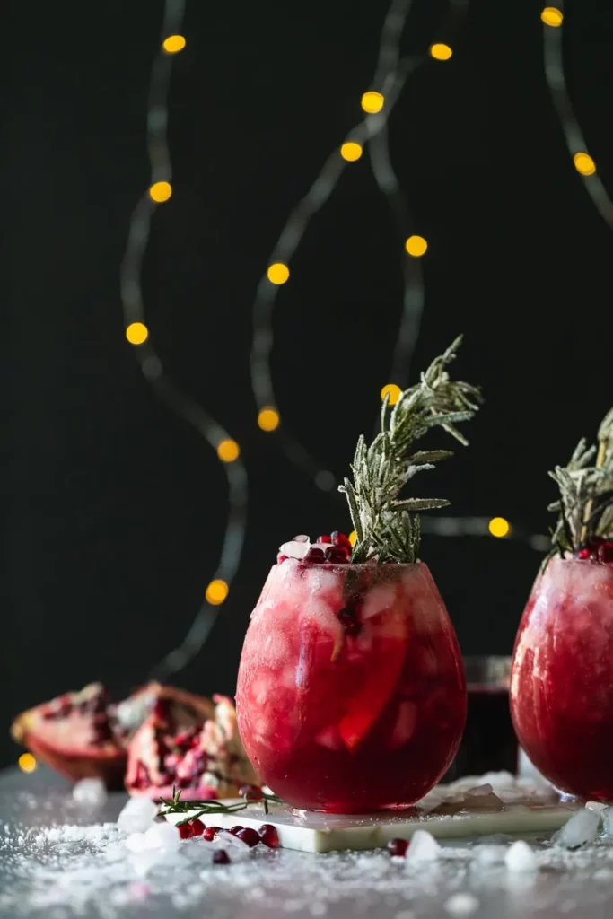 Pomegranate-Paloma-5 - Festive & Easy: Master the Perfect Pomegranate Paloma Festive pomegranate cocktail with rosemary garnish, against a backdrop of twinkling lights. Perfect for holiday celebrations.