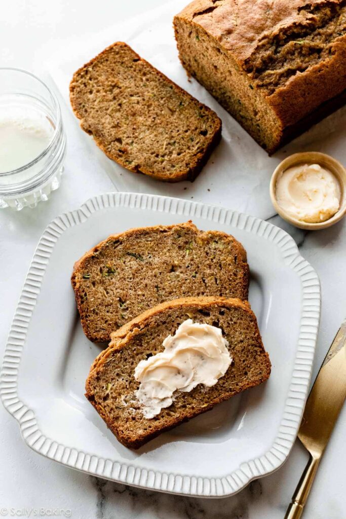 easy-homemade-zucchini-bread-3 - Versatile Zucchini Bread Recipe: Nutty, Chocolate, or Spiced Slices of homemade zucchini bread with butter on a plate, ready to enjoy as a delicious breakfast treat.
