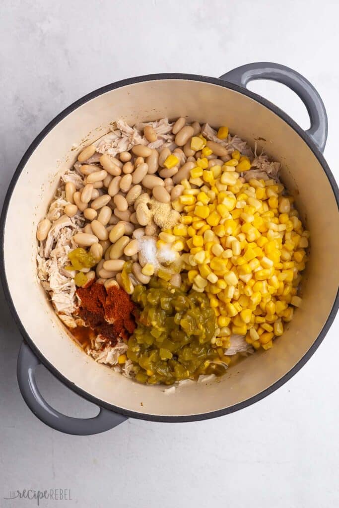 k - Your Guide to Delicious White Chicken Chili with Easy Tips Pot with white chicken chili ingredients: shredded chicken, beans, corn, green chiles, spices, ready for cooking.