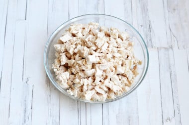 salat-s-syrom-greckimi-orexami_1615529844_2_max - Make Delicious Chicken Salad with Walnuts & Cheese in Minutes Bowl of diced chicken breast on a wooden table, perfect for salads, sandwiches, or meal prep recipes.