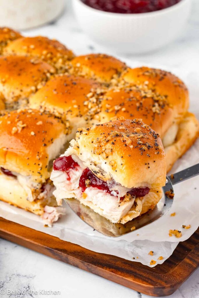 Turkey and cranberry sliders with poppy seed topping on a tray, perfect for holiday gatherings and parties.