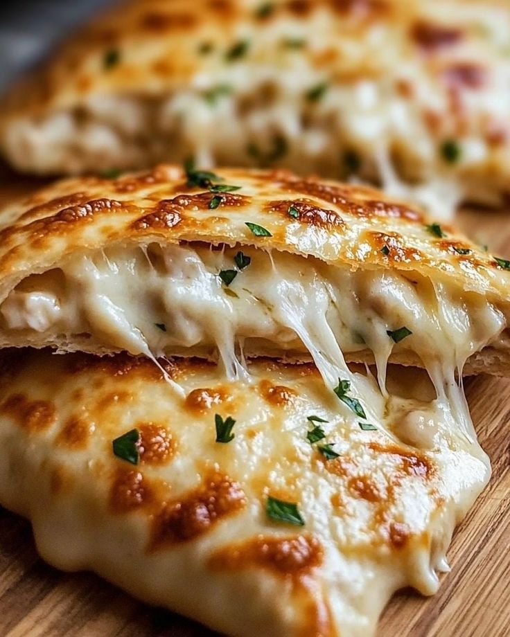 Cheesy calzone with gooey mozzarella and sprinkled herbs, fresh from the oven on a wooden board. Cheesy Chicken Calzone
