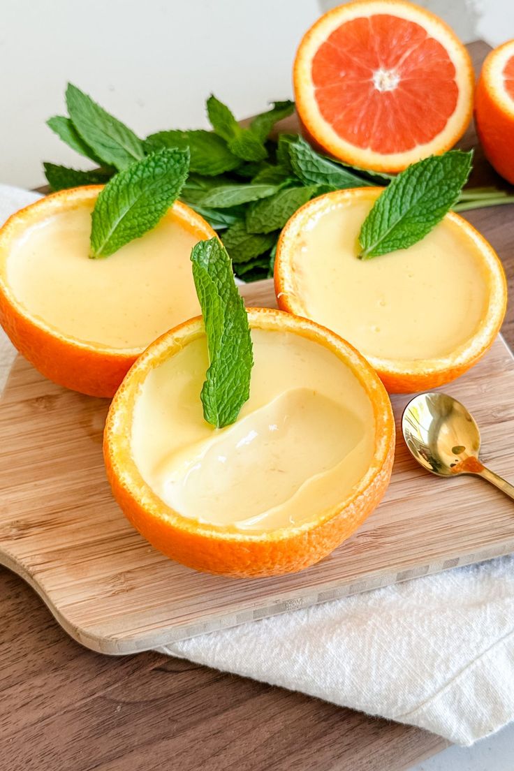 Orange-themed desserts in orange cups garnished with fresh mint leaves on a wooden board.